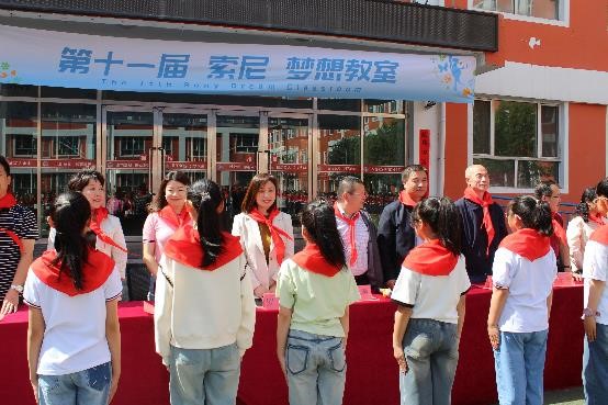 西關(guān)小學(xué)的孩子們?yōu)楝F(xiàn)場嘉賓佩戴紅領(lǐng)巾